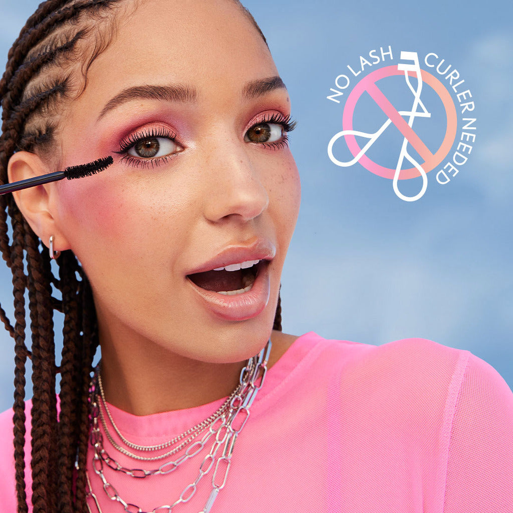 Model applying Eye Enhancer 3D Waterproof Mascara with a bright pink background.